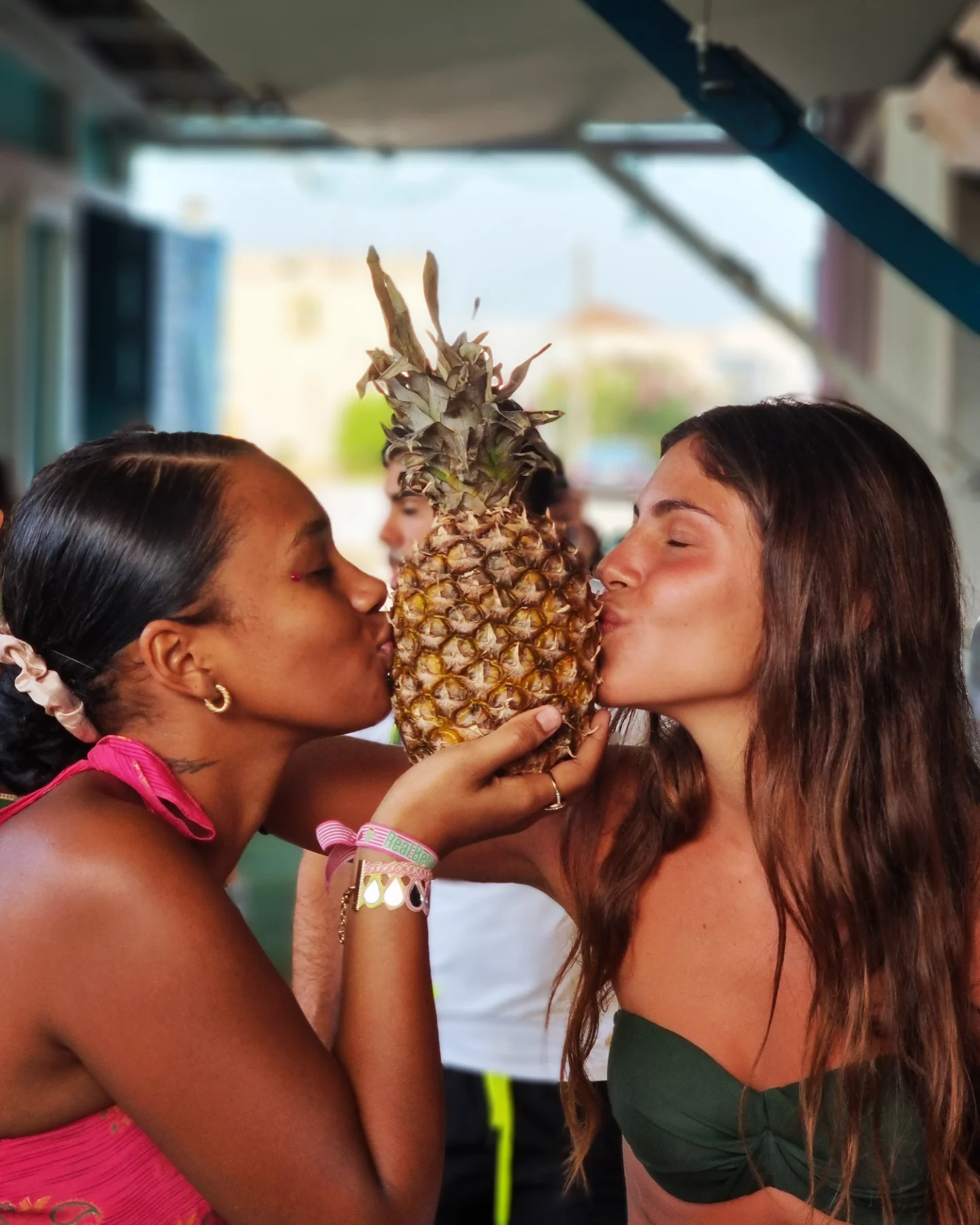 Dos amigas besando una piña al sol